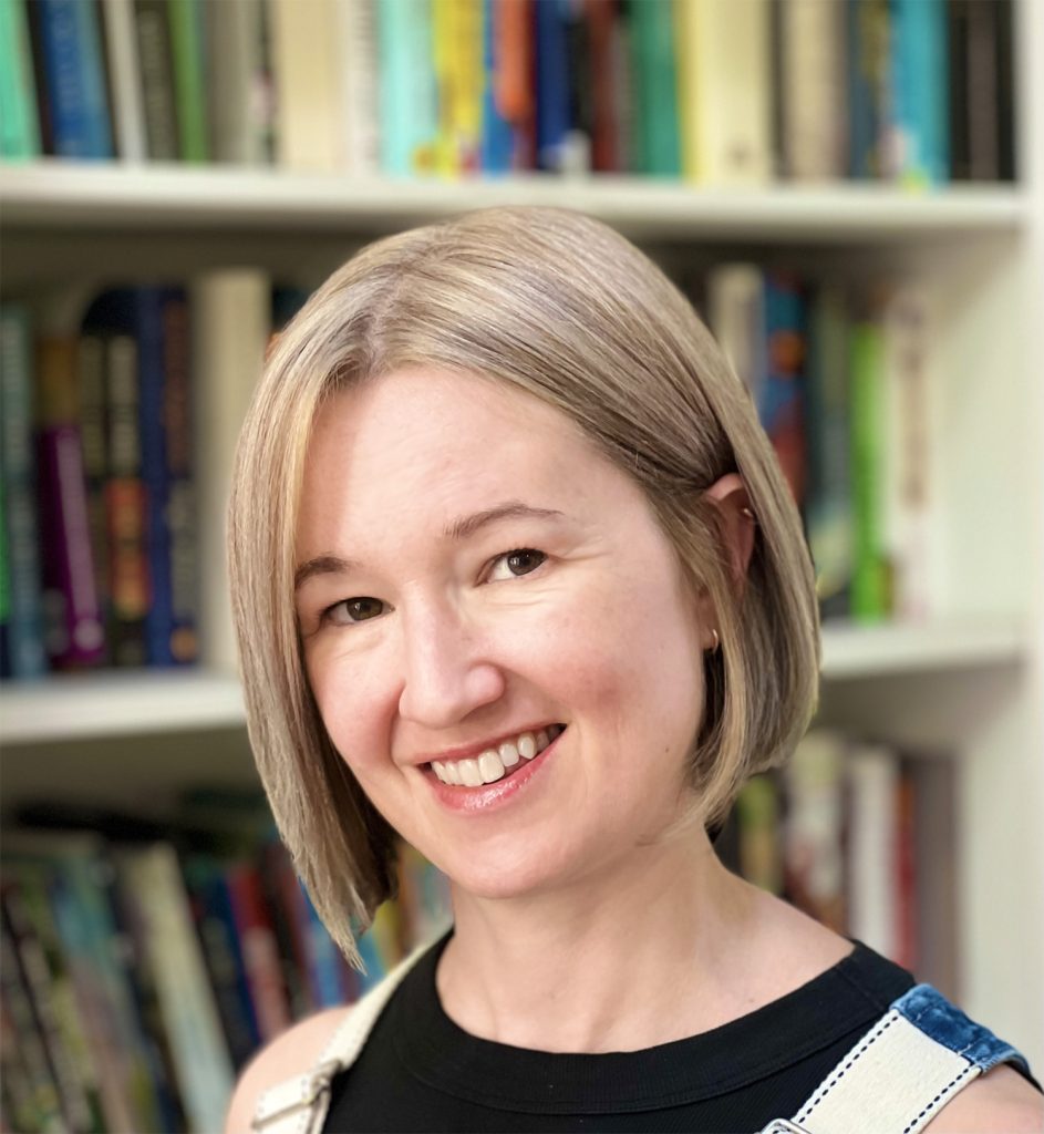 Illustrator Heather Brockman Lee smiling for the camera in front of a bookcase. 